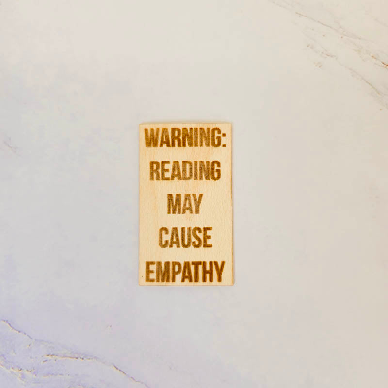 Maple wood sticker, natural finish, laser-engraved with the phrase Reading causes empathy in clear script.