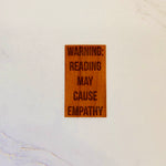 Cherry wood sticker with engraved text: WARNING: READING MAY CAUSE EMPATHY. Warm finish, rectangular shape, handmade.