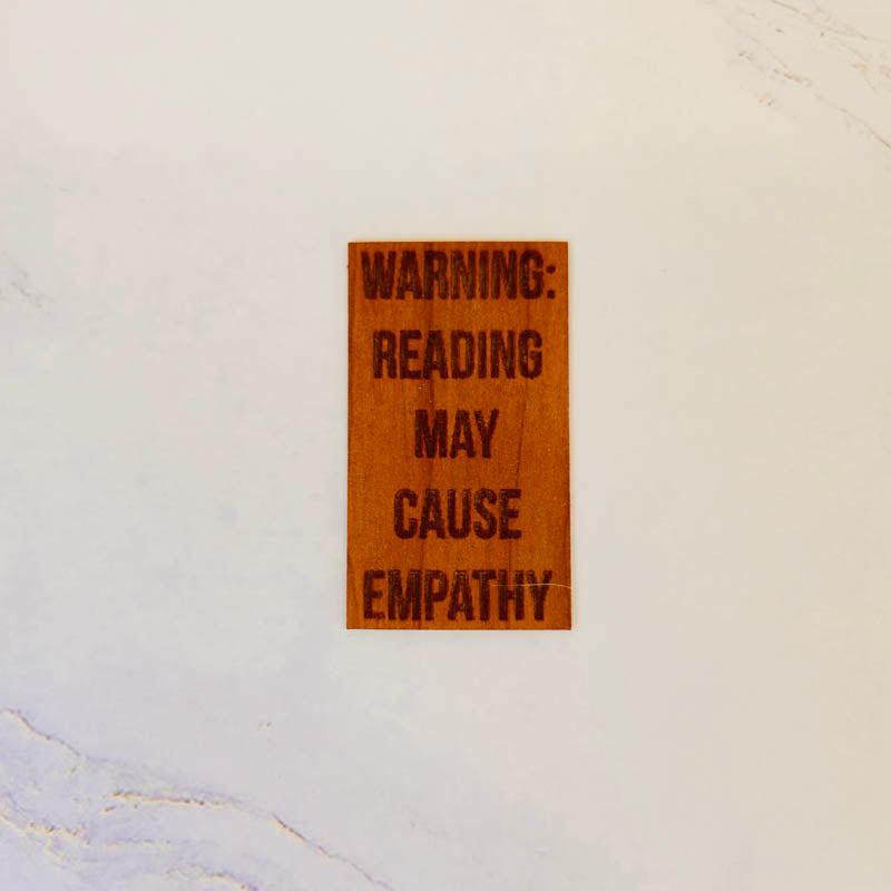 Cherry wood sticker with engraved text: WARNING: READING MAY CAUSE EMPATHY. Warm finish, rectangular shape, handmade.