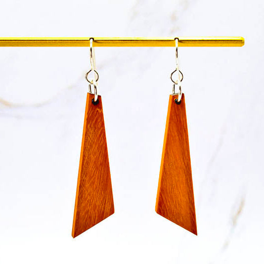 Wooden earrings hanging from a gold rod on a white background
