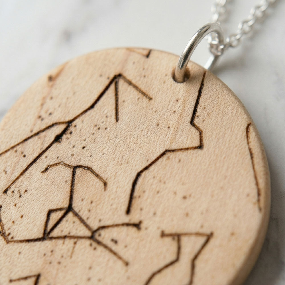 Personalized olivewood necklace with engraved star-chart constellations on a silver chain; light wood finish, laser-etched details.