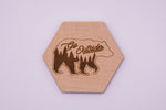 Hexagonal wooden coaster with bear design and 'Go Outside' text on a light purple background
