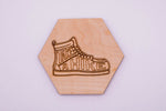 Hexagonal wooden coaster with a laser-cut shoe design and 'Take a Hike' text on a light purple background.