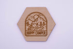 Hexagonal wooden coaster with 'Happy Camper' design on a white background