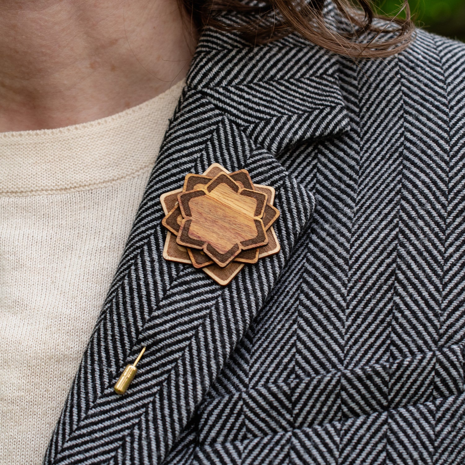 Wooden brooch on a person wearing a patterned coat