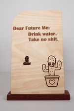 Handmade wooden message board with clip, natural finish, engraved “Dear Future Me: Drink water. Take no shit.” with cactus design.