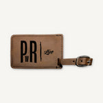 Dark brown leatherette luggage tag, back, laser engraved with the PRWMade Live logo, with buckle strap