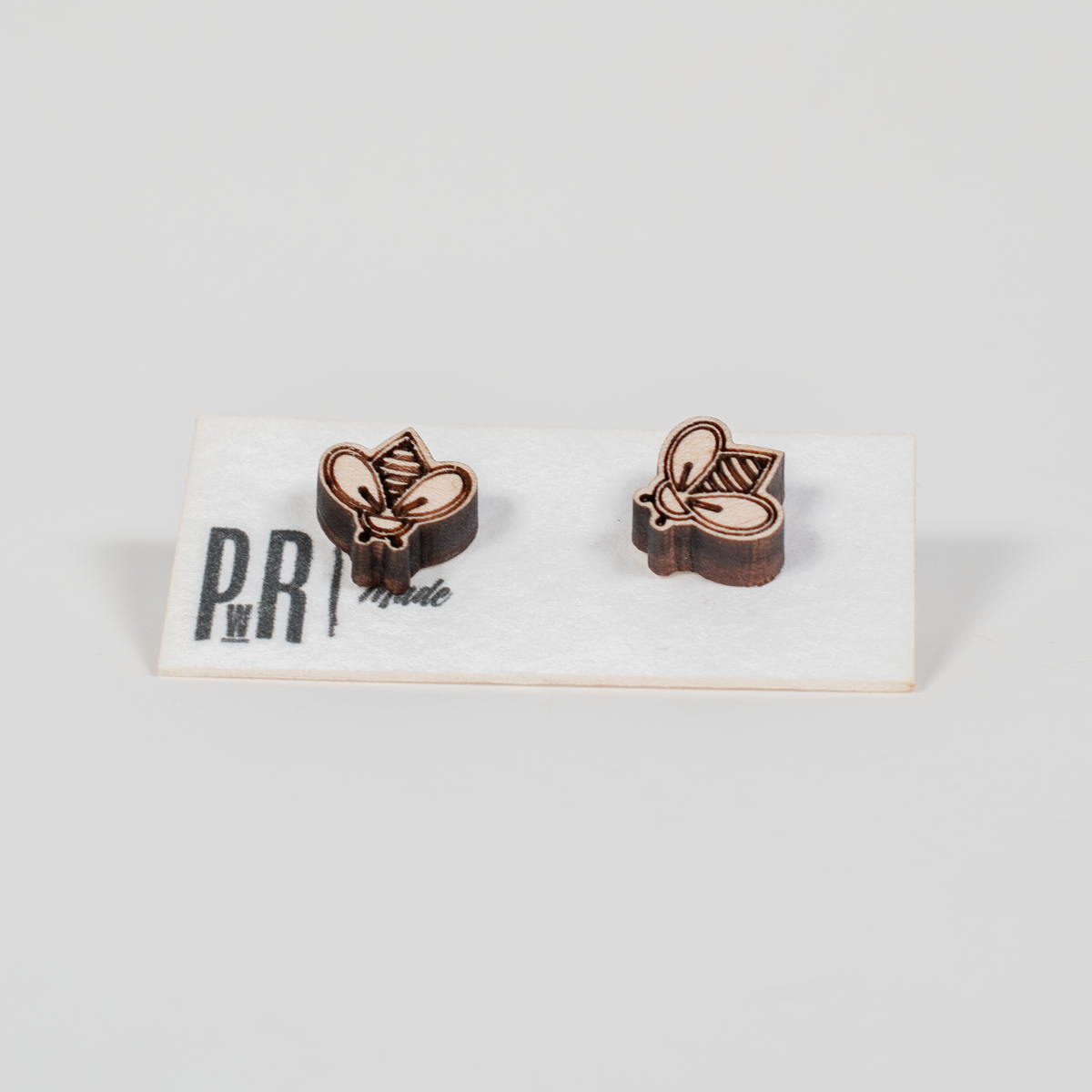 Handcrafted wooden stud earrings with geometric engraving, natural finish, displayed on a white PRW Made logo card.