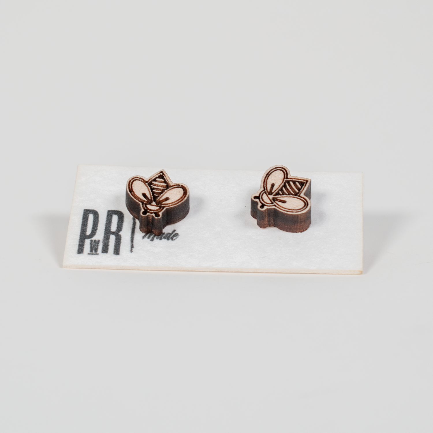 Handcrafted wooden stud earrings with geometric engraving, natural finish, displayed on a white PRW Made logo card.