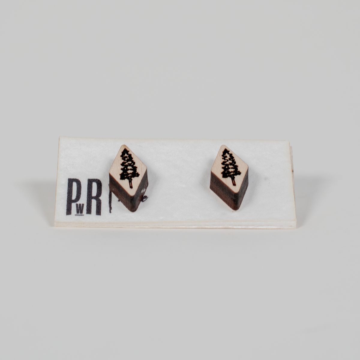 Handmade wood stud earrings with geometric shape, laser-engraved pine tree design, natural finish, hypoallergenic posts.