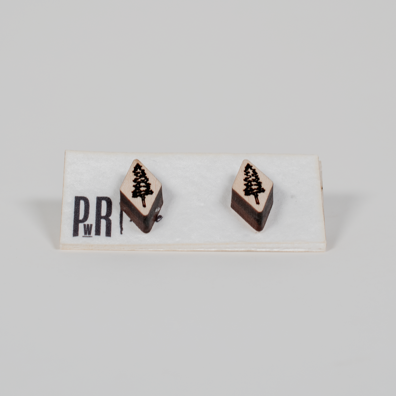 Handmade wood stud earrings with geometric shape, laser-engraved pine tree design, natural finish, hypoallergenic posts.