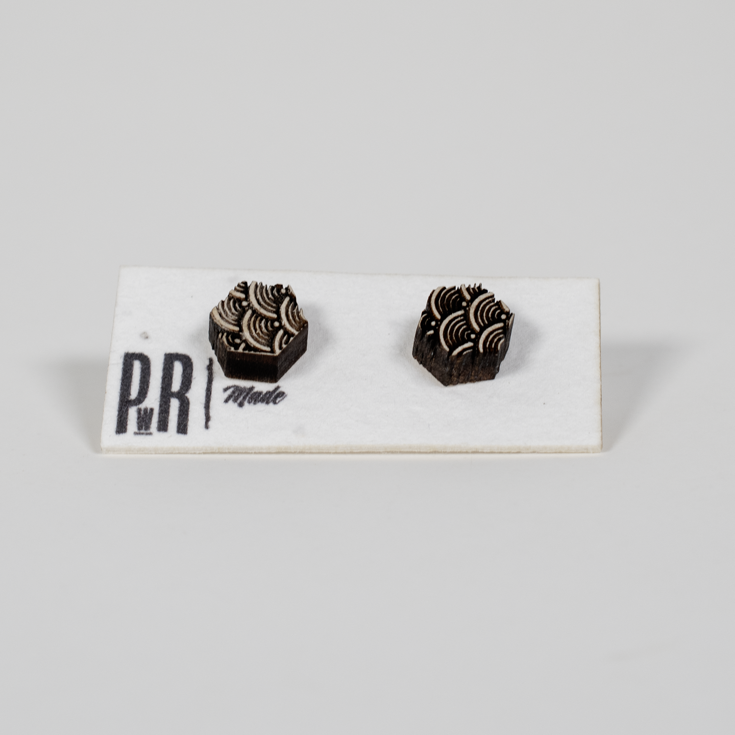 Geometric wood stud earrings with detailed laser-engraved patterns, natural finish, displayed on a white PRW Made card.