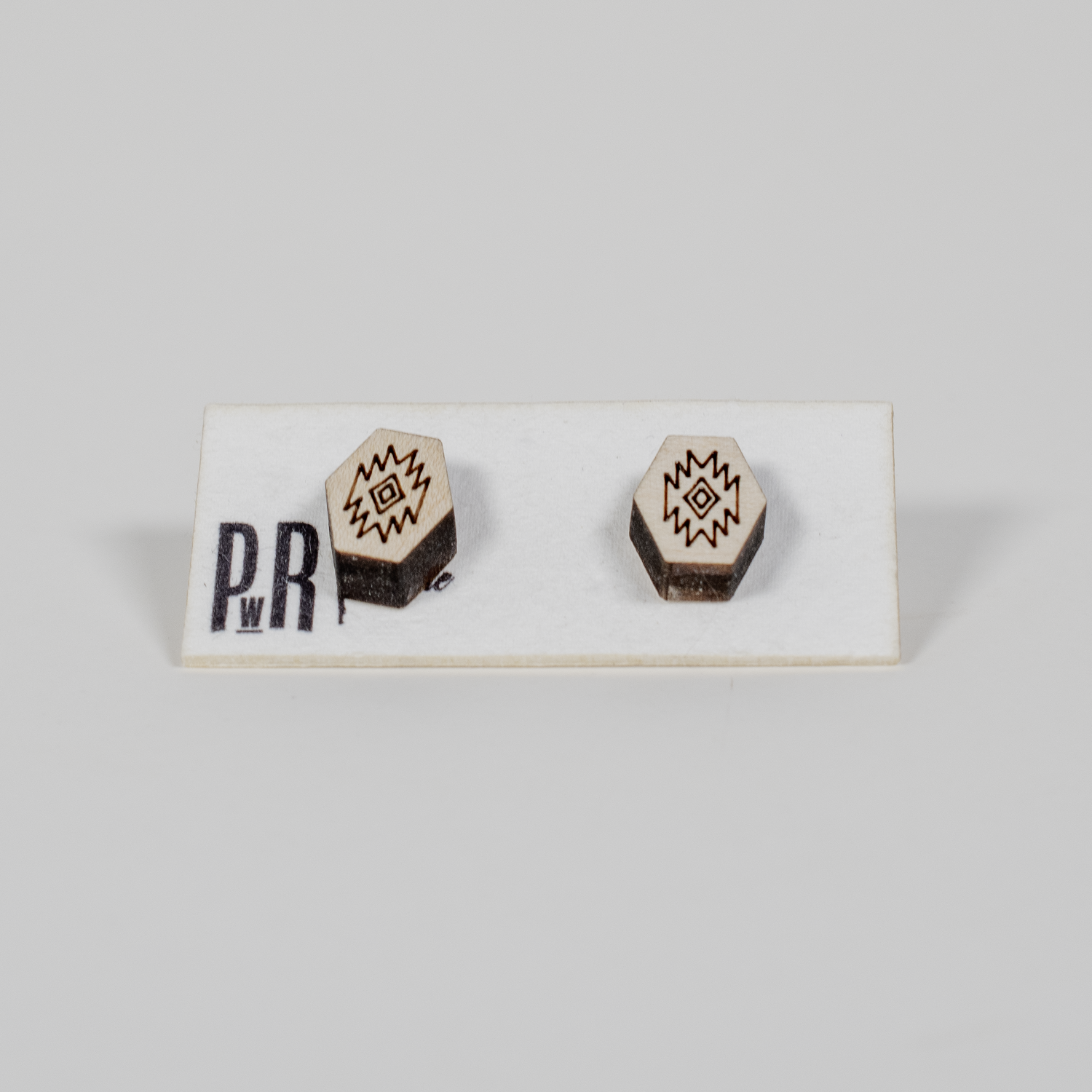 Hexagonal wood stud earrings with black geometric engraving, hypoallergenic posts, displayed on a PRW Made white card.