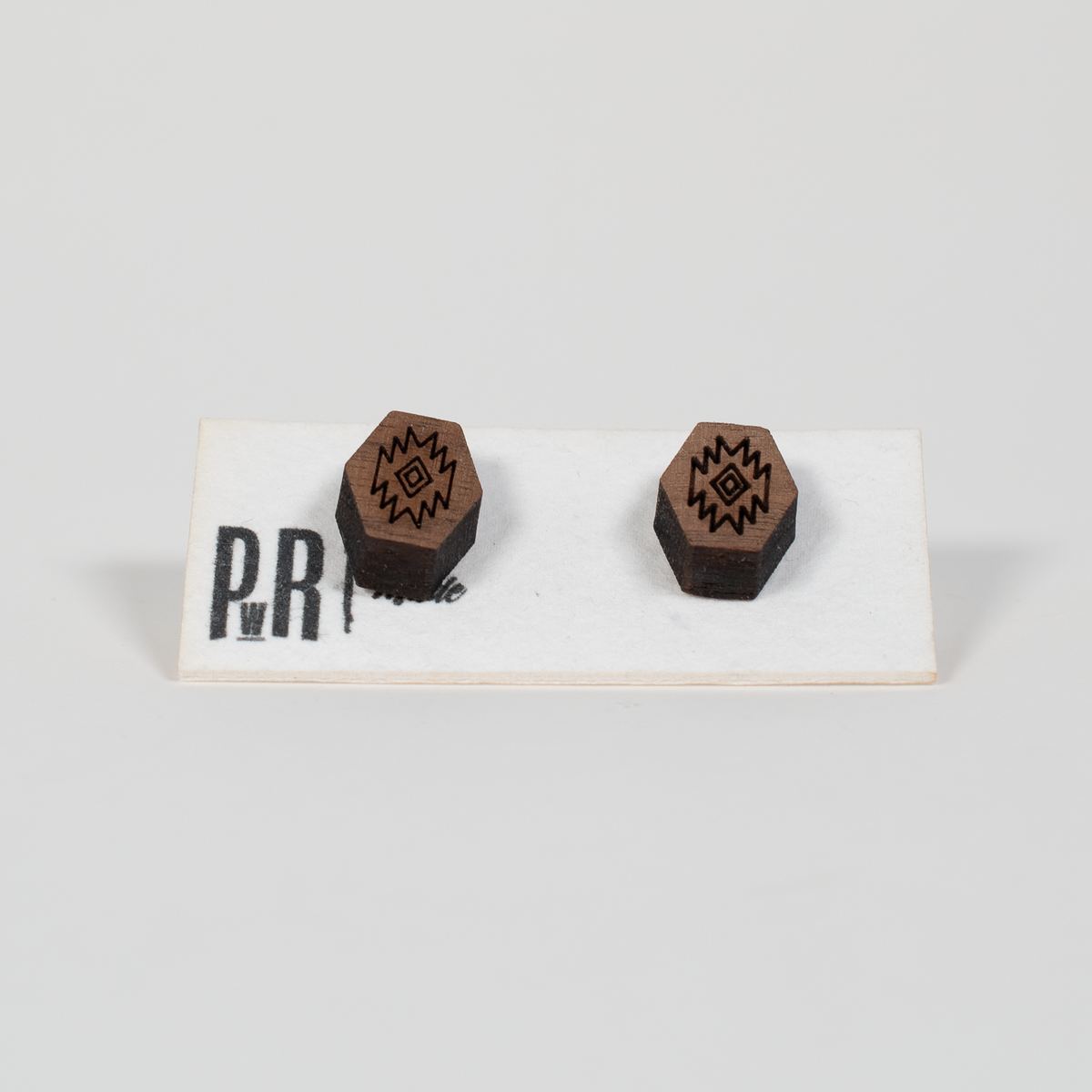 Walnut wood stud earrings with laser-engraved geometric design, hypoallergenic posts, displayed on PRW Made branded card.