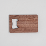 Walnut wood veneer wallet bottle opener with smooth finish, shown next to a rectangular walnut cutting board with handle cutout.