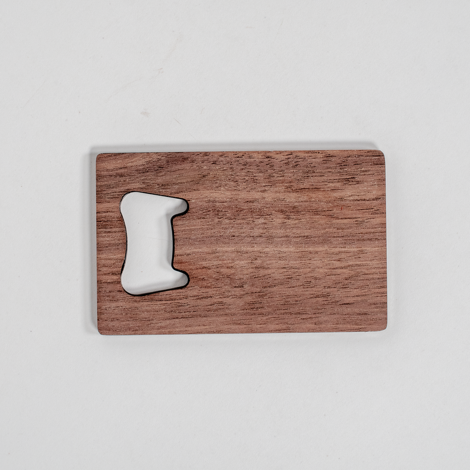 Walnut wood veneer wallet bottle opener with smooth finish, shown next to a rectangular walnut cutting board with handle cutout.