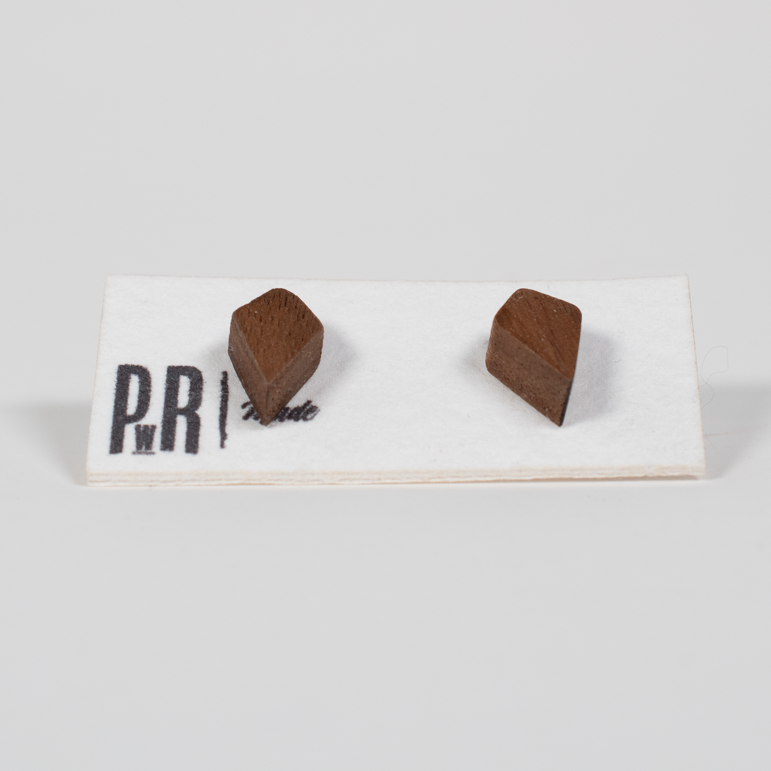 Fire Wood Stud Earrings—two small, brown geometric wood studs on card; handcrafted, hypoallergenic, laser-engraved finish.