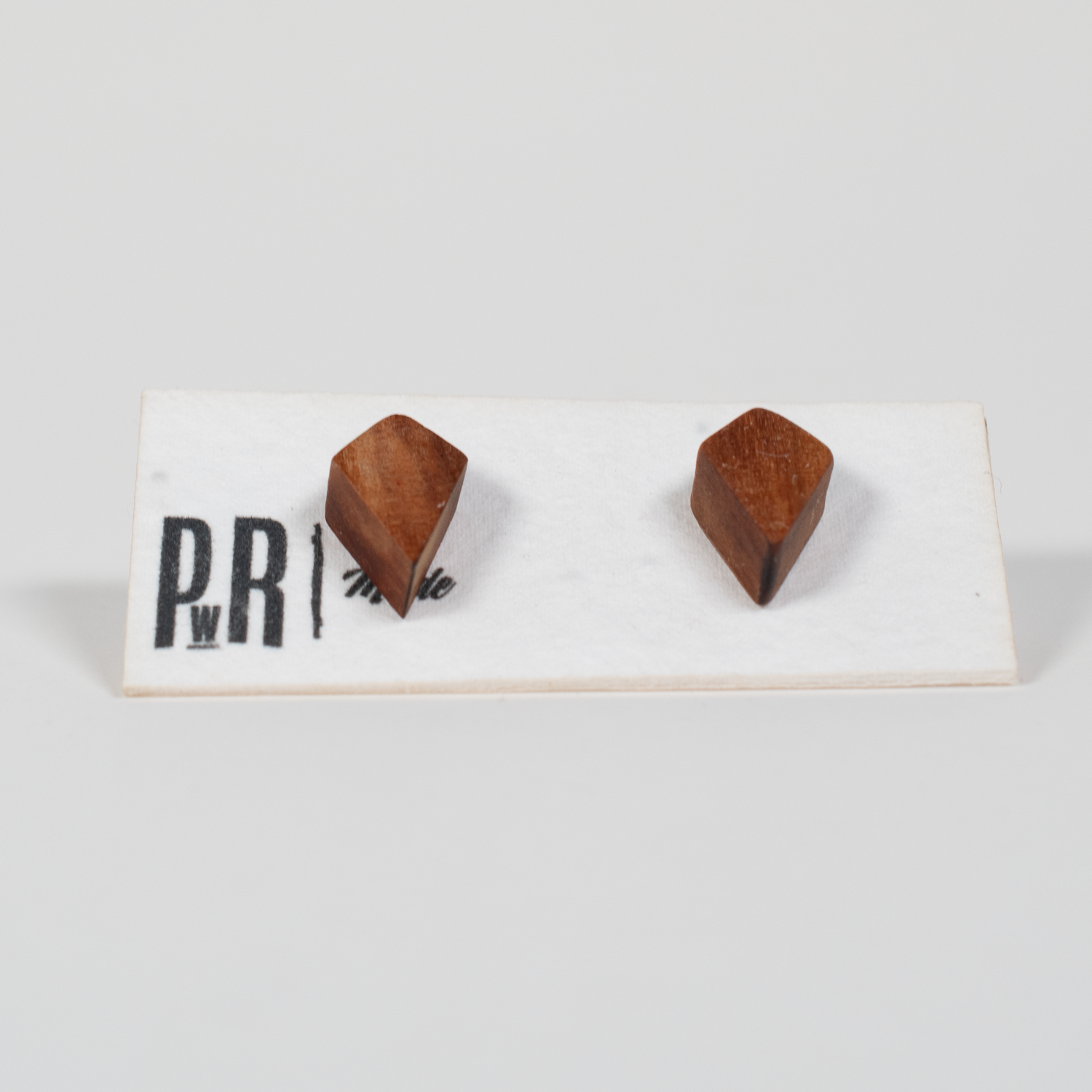 Fire-shaped wood stud earrings, laser-engraved with a flame design. Natural wood finish on a white PRW Made display card.
