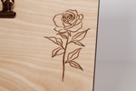 Laser-engraved wooden message board with clip, featuring a detailed rose with leaves and stem on natural wood finish.