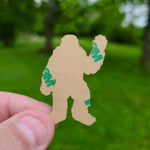Person holding a sticker cutout of a creature with '