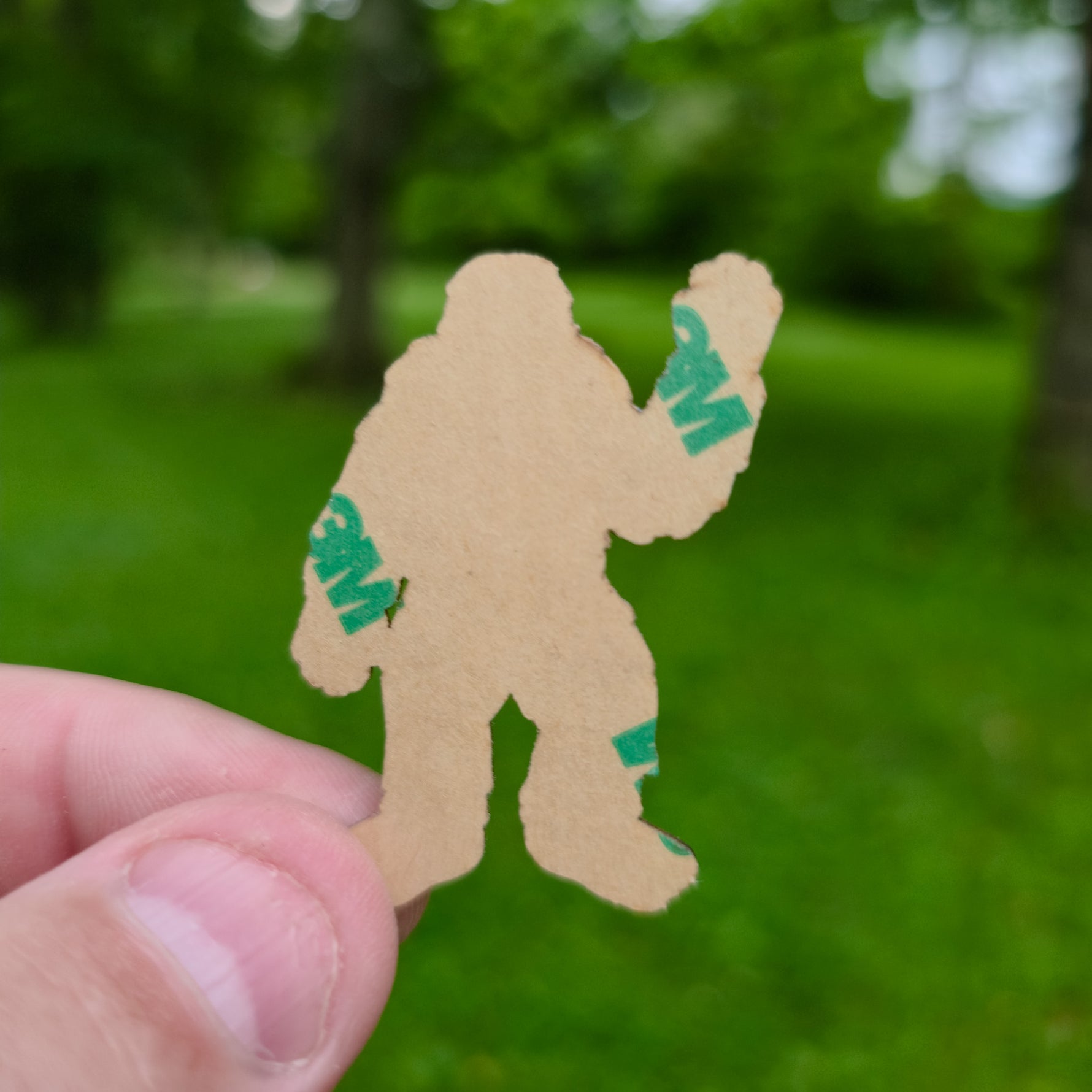 Person holding a sticker cutout of a creature with '