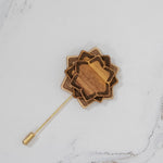 Wooden flower-shaped lapel pin on a marble surface