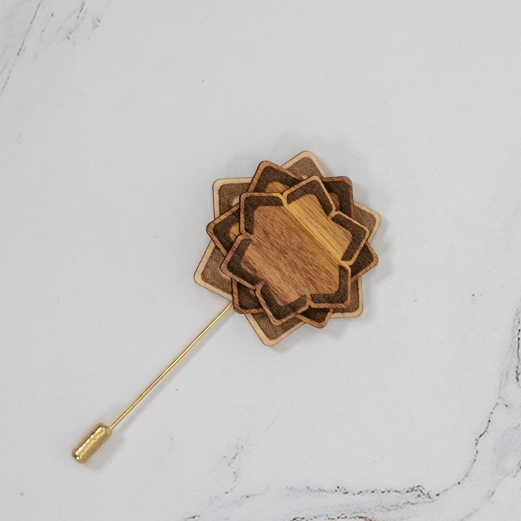 Wooden flower-shaped lapel pin on a marble surface