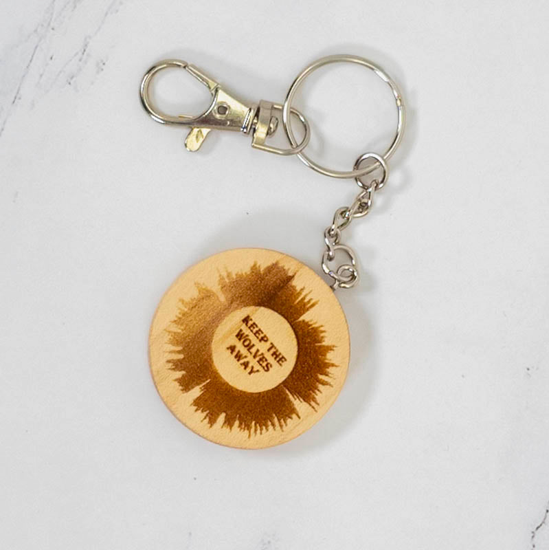 Round maple wood keychain laser engraved with a sunburst and custom text reading Keep The Wolves Away, silver clasp, personalized by PRWMade