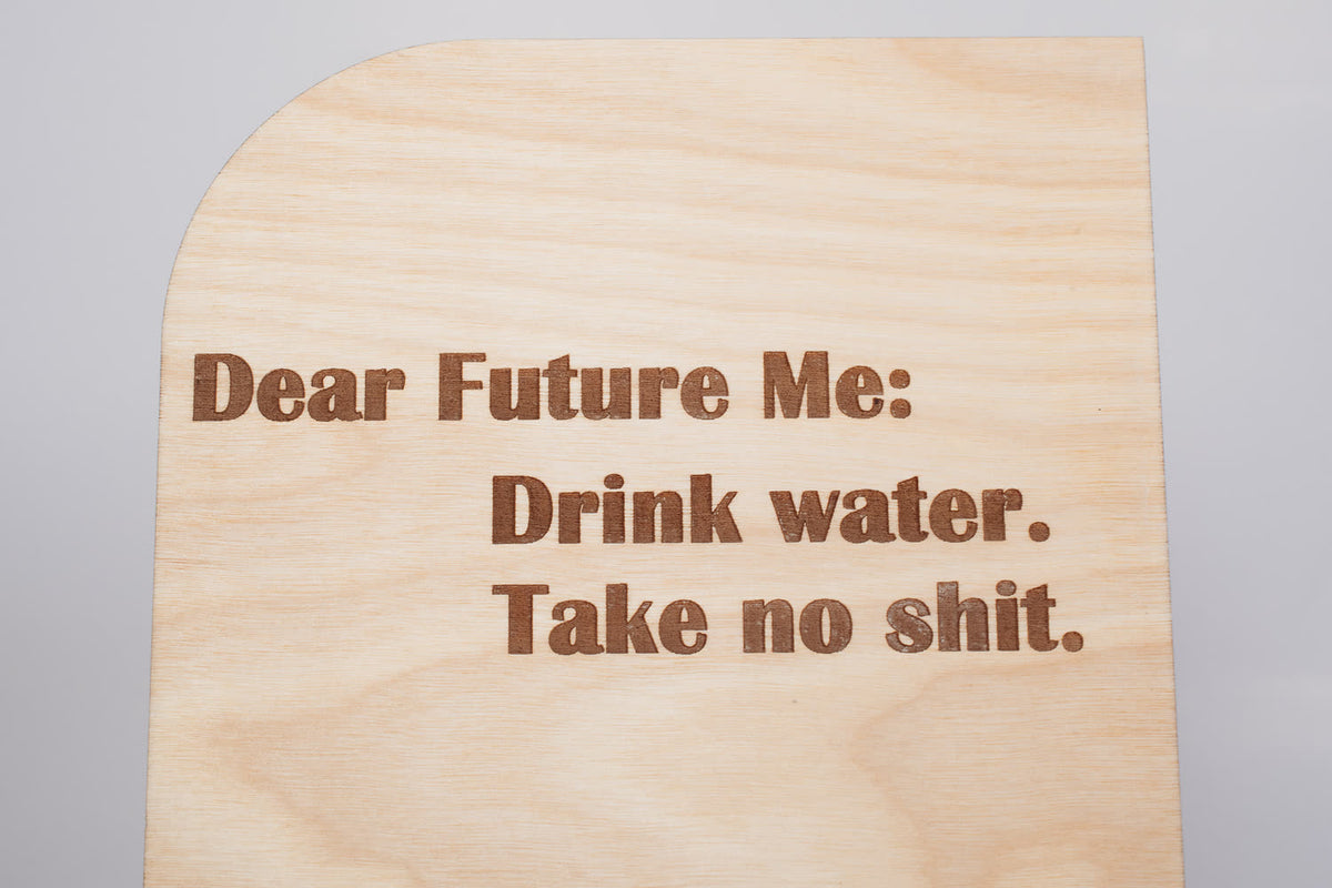 Close-up of the engraved Dear Future Me lettering on a wooden message board, showing crisp laser engraving on wood grain