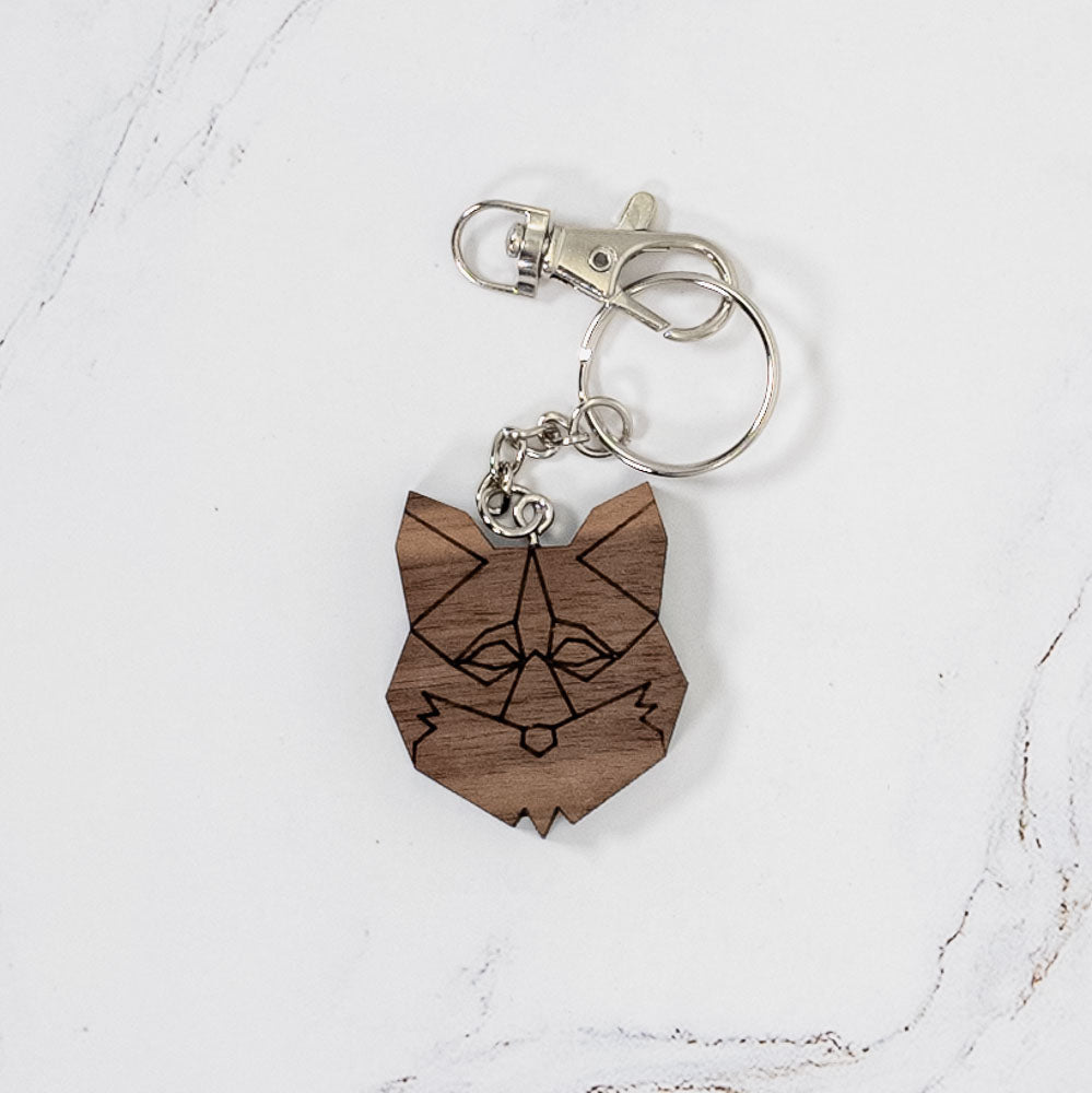 Geometric fox wood keychain in walnut, laser cut with low-poly faceted line art and a silver clasp and split ring, handmade in Ohio by PRWMade