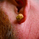 Wooden earbud in a person's ear with a close-up view of the ear and beard.
