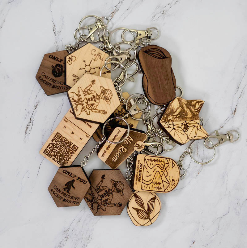 The geometric half fox keychain shown alongside the full PRWMade wooden keychain collection in maple and walnut