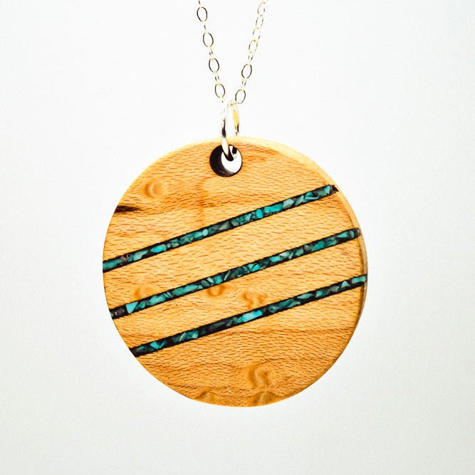 Handmade round wood pendant with three turquoise stone inlays, smooth finish, on sterling silver chain, displayed on white background.