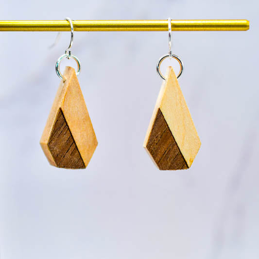 Wooden geometric earrings on a gold rod against a light gray background