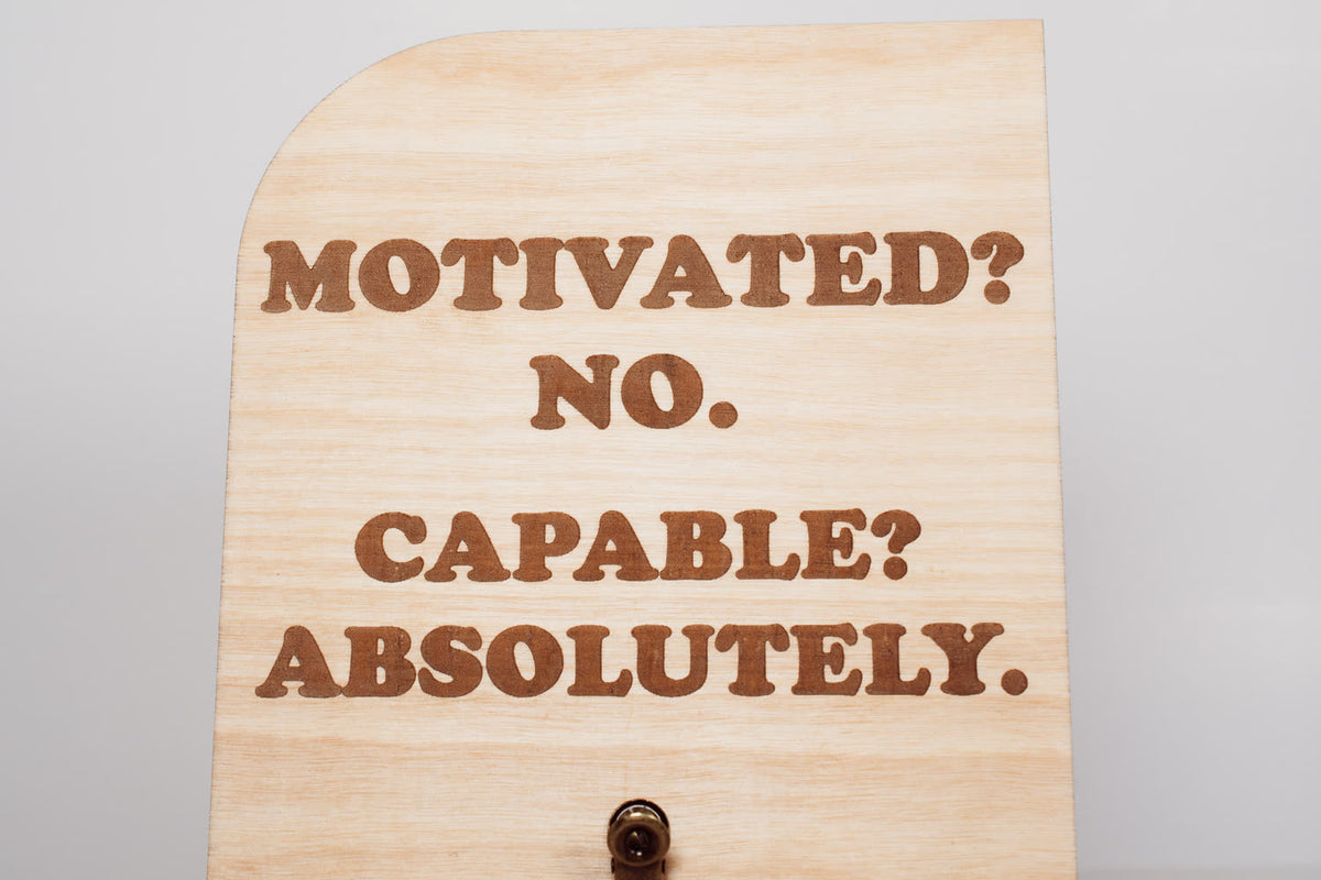 Close-up of the laser engraved Motivated? No. Capable? Absolutely. lettering on a wooden message board by PRWMade