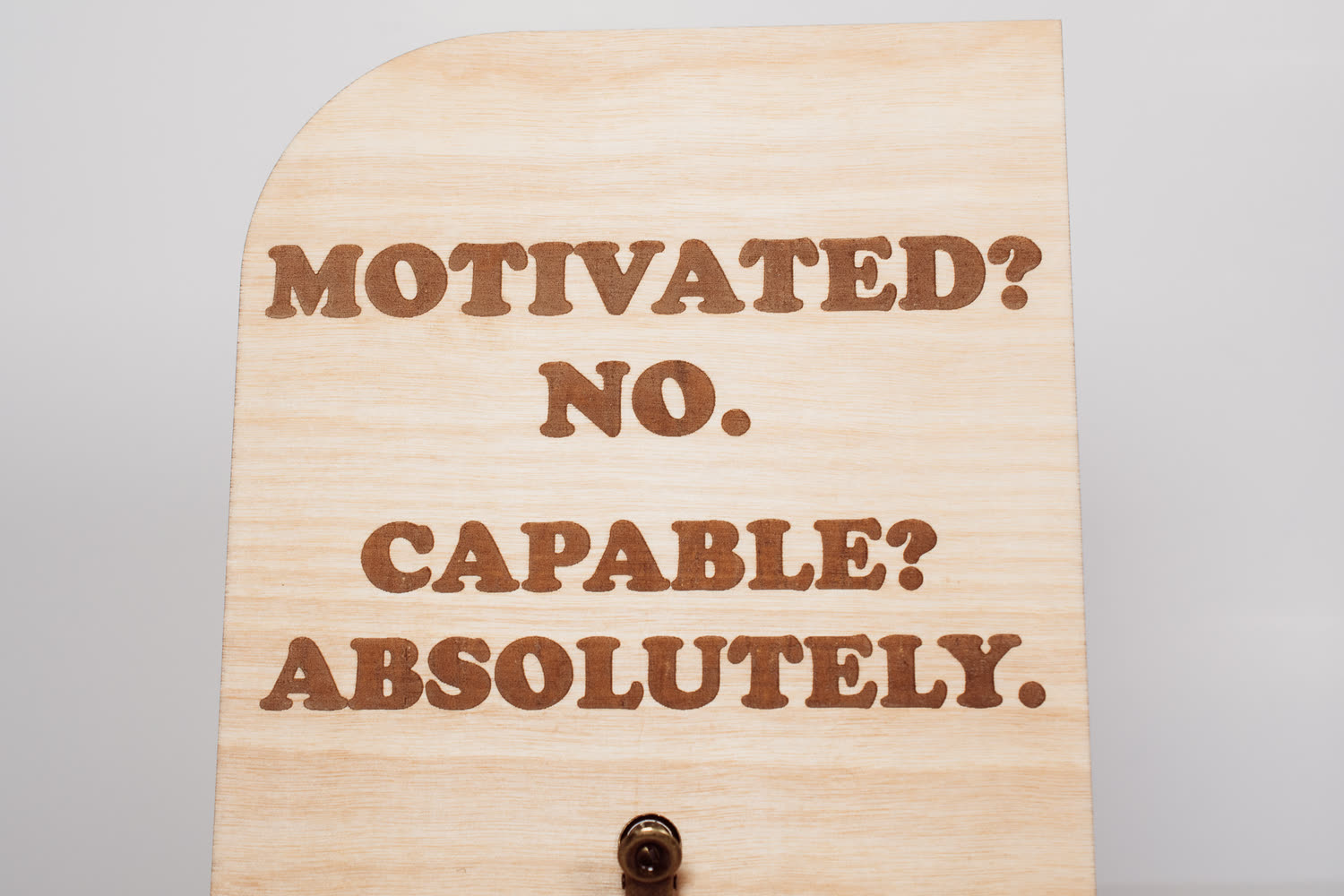 Close-up of the laser engraved Motivated? No. Capable? Absolutely. lettering on a wooden message board by PRWMade