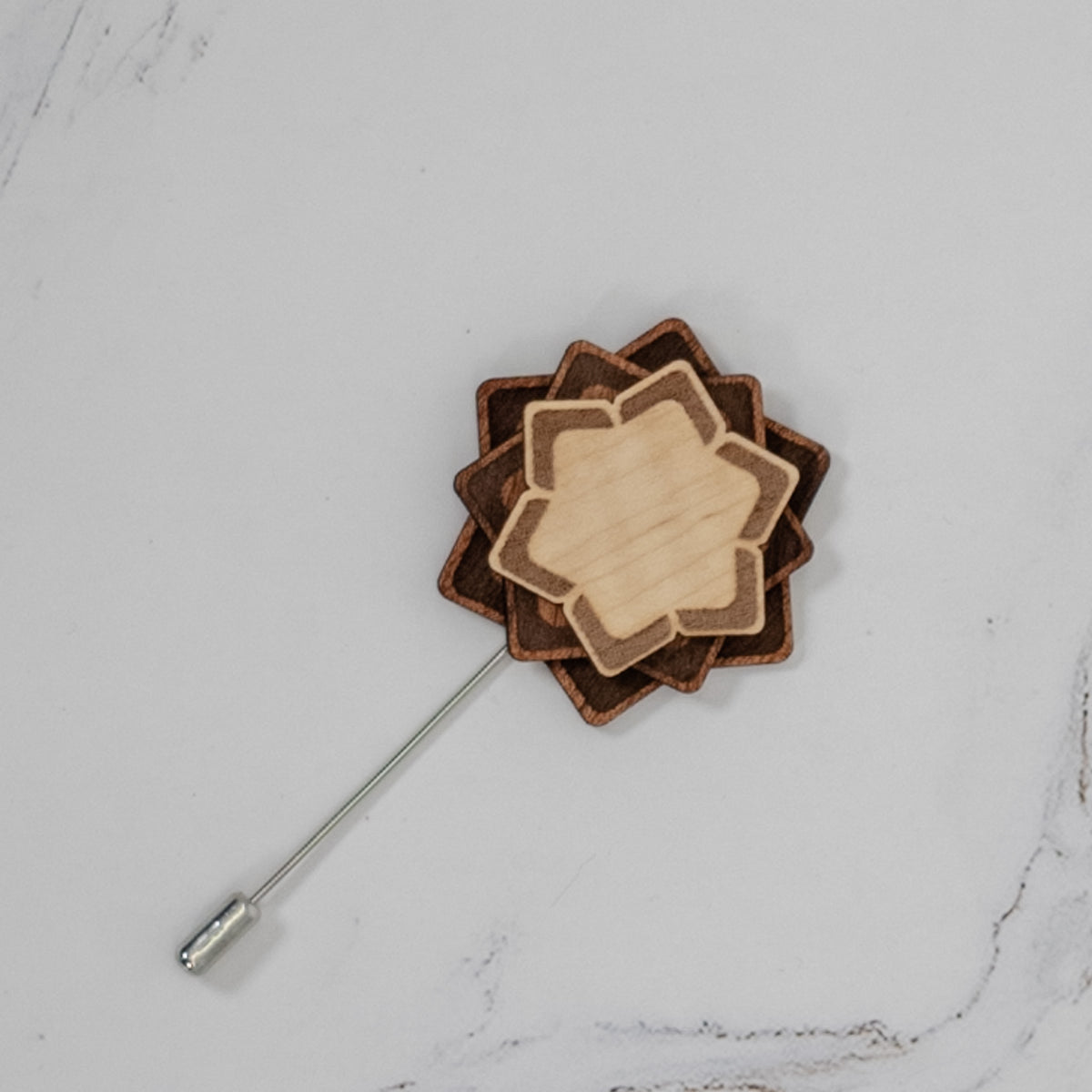 Wooden lapel pin with layered design on a marble surface