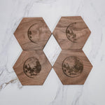 Four walnut moon phase coasters in a 2x2 flat lay on marble, crescents and full moons