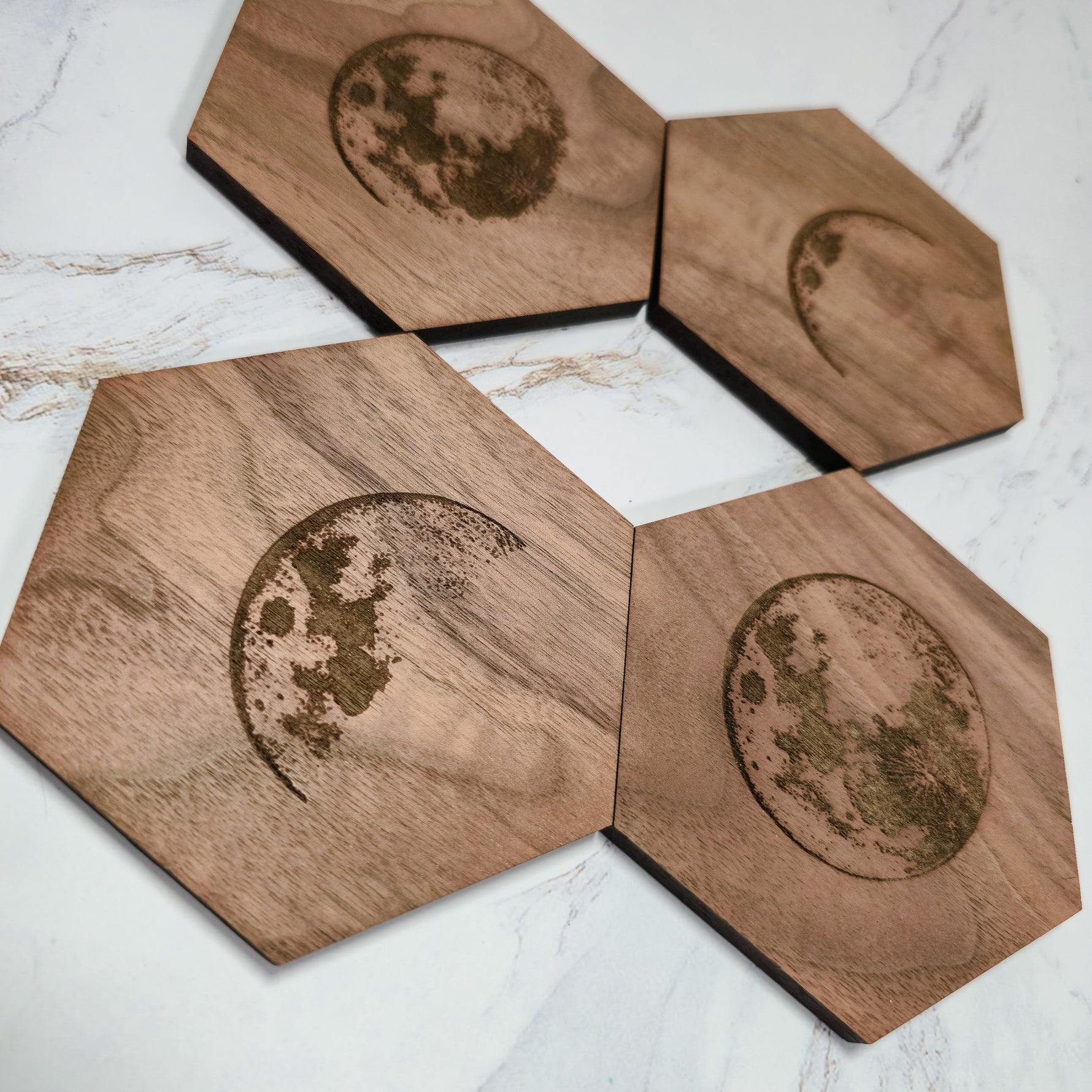 Walnut moon phase coaster set angled on marble, waxing crescent and full moon engravings