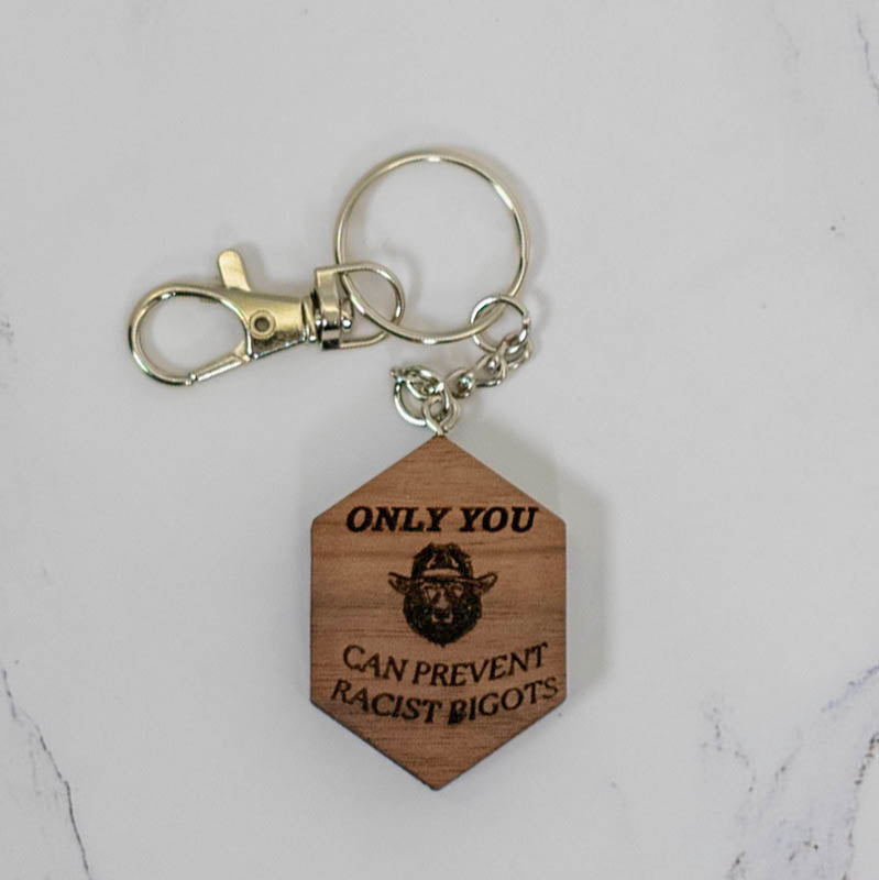 Walnut hexagon wood keychain laser engraved with a Sasquatch face and the words Only You Can Prevent Racist Bigots, handmade in Ohio by PRWMade
