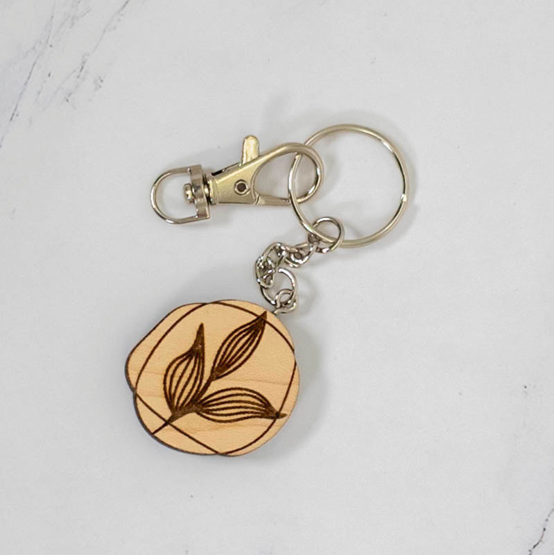 Small round maple wood keychain engraved with a two-leaf botanical line drawing, silver clasp and split ring, handmade in Ohio by PRWMade