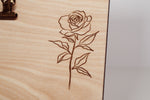 Detail of a laser engraved rose with stem and leaves on a natural wood message board, fine line engraving by PRWMade