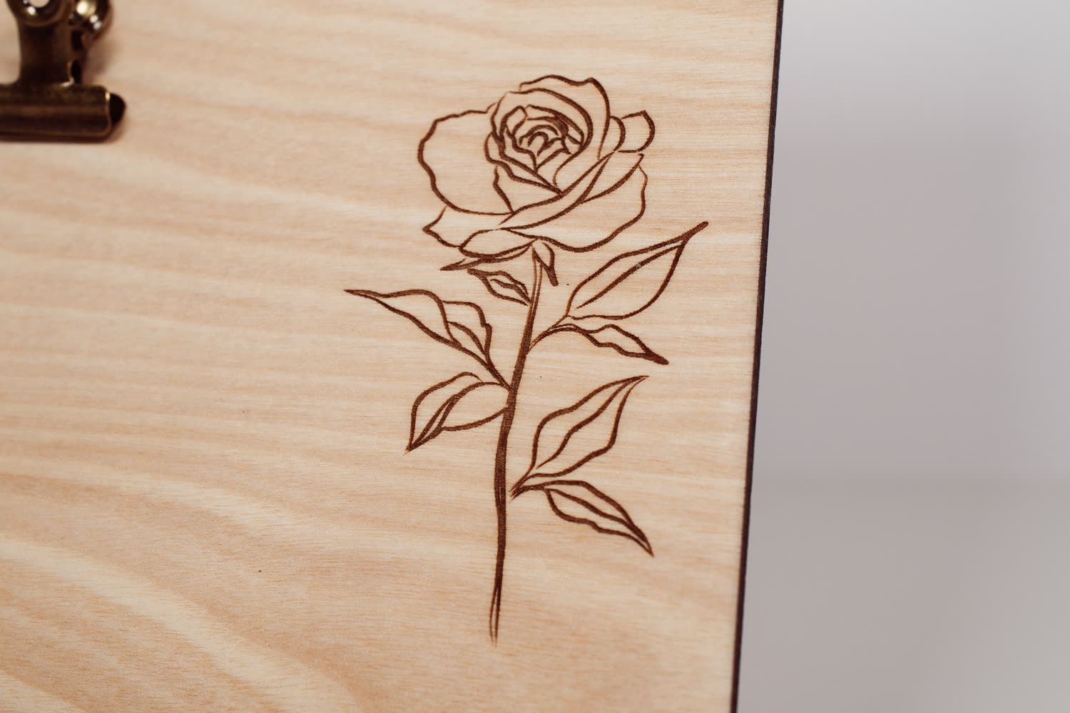 Detail of a laser engraved rose with stem and leaves on a natural wood message board, fine line engraving by PRWMade